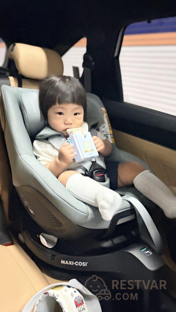 카시트에 앉아 우유팩을 들고 있는 16개월 아기