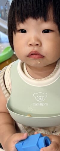 베이비뵨 민트색 실리콘 턱받이를 하고 하이체어에 앉은 16개월 아기