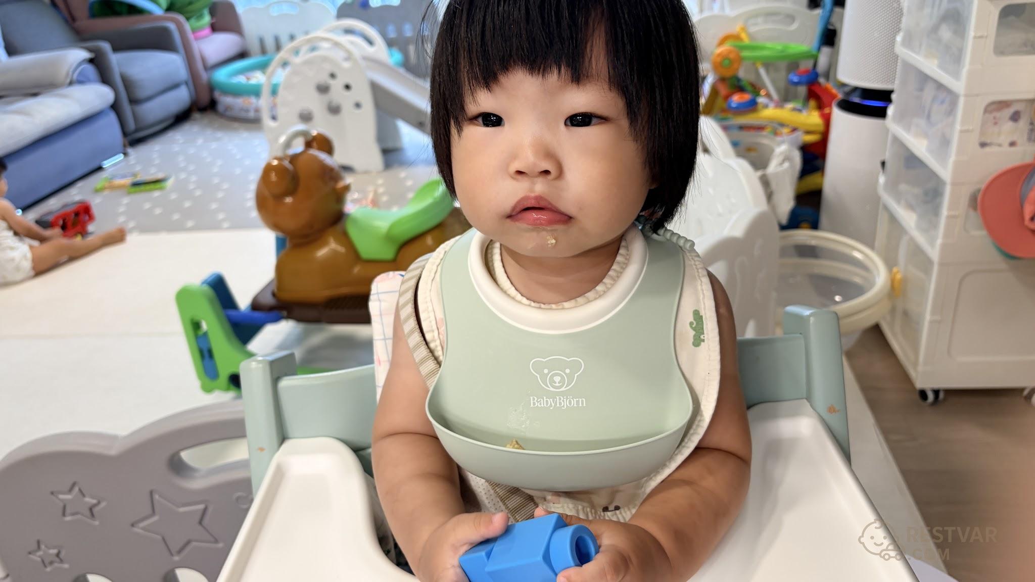 베이비뵨 민트색 실리콘 턱받이를 하고 하이체어에 앉은 16개월 아기