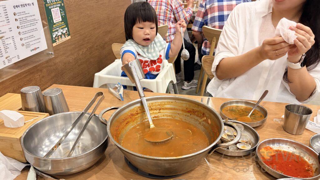 국자를 들고 냄비 쪽으로 손을 뻗는 16개월 아기