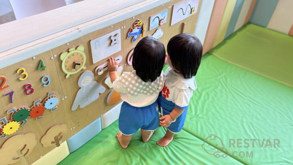키즈존 원목 액티비티 보드 앞에 나란히 선 16개월 쌍둥이